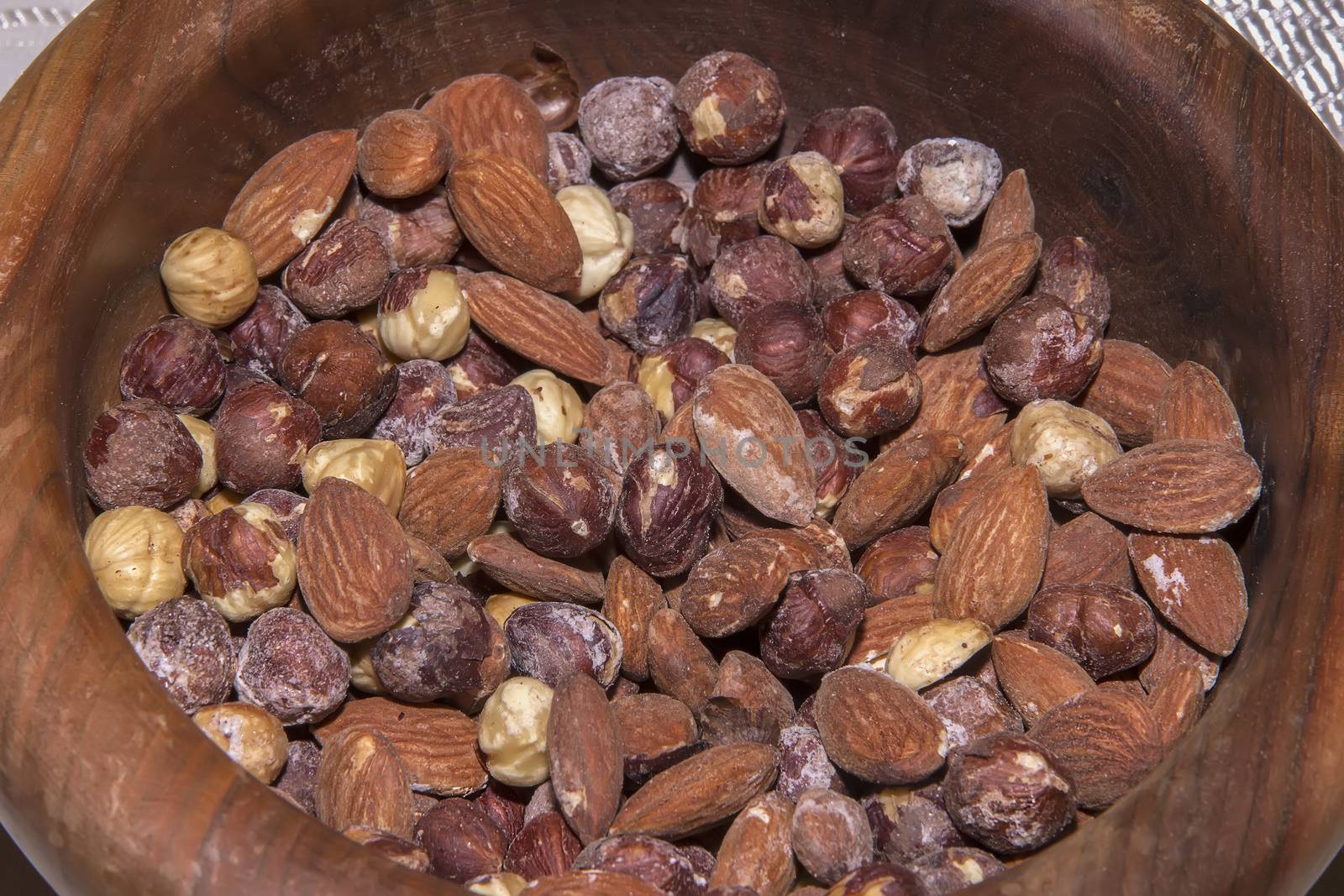 Lots of roasted almonds, hazelnuts in wooden bowl. Close