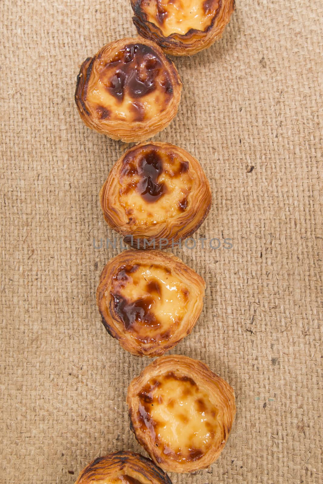 Famous Portuguese egg pastry tart called 'Pastel de Belem' on hessian fabric.