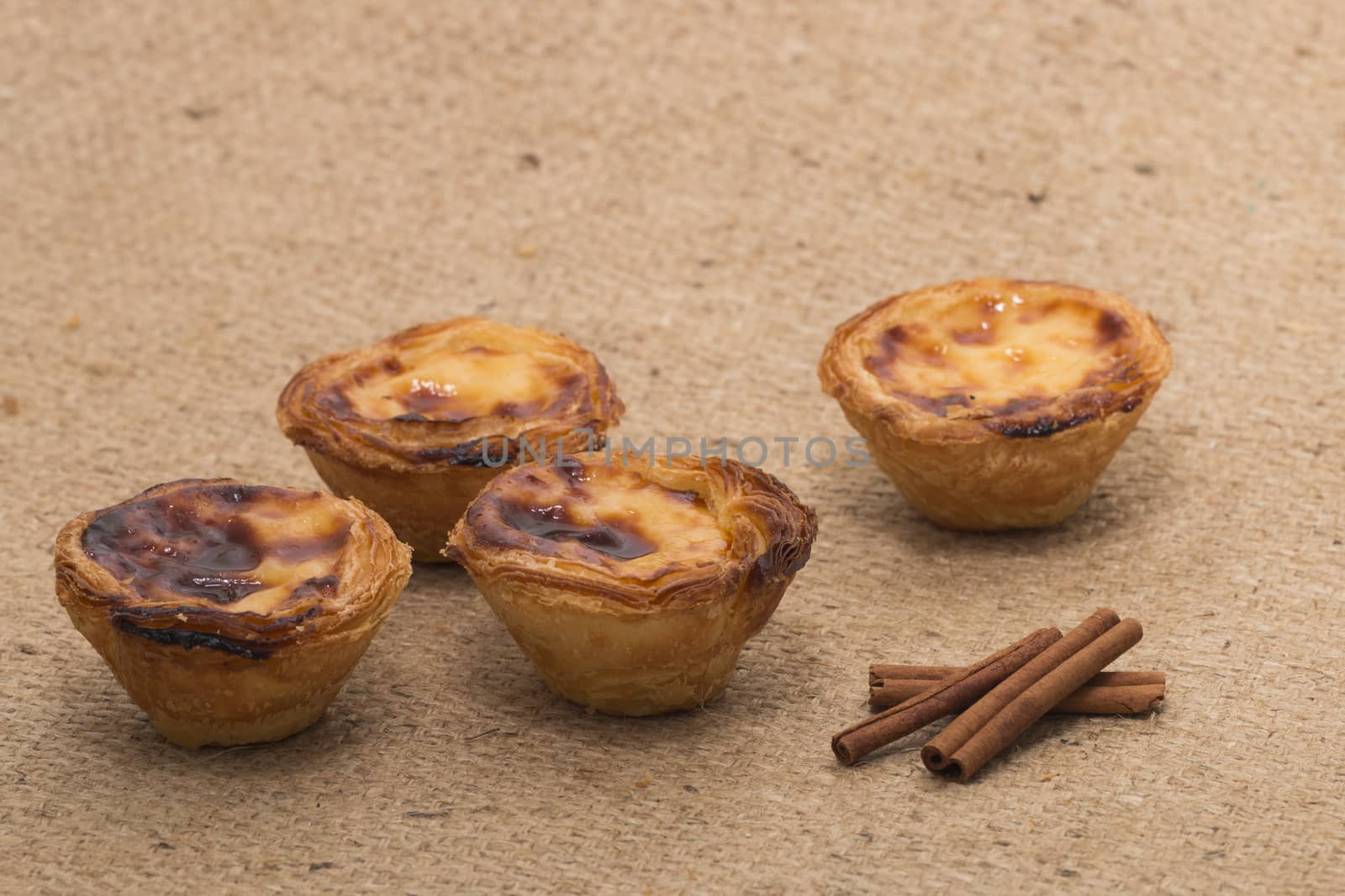 Famous Portuguese egg pastry tart called 'Pastel de Belem' on hessian fabric.