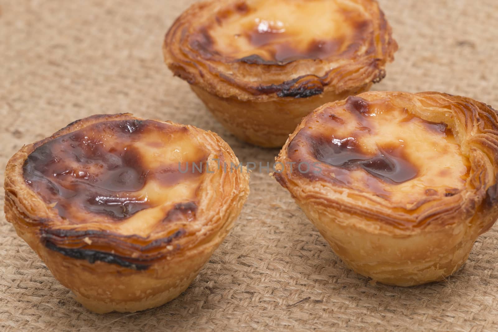 Famous Portuguese egg pastry tart called 'Pastel de Belem' on hessian fabric.