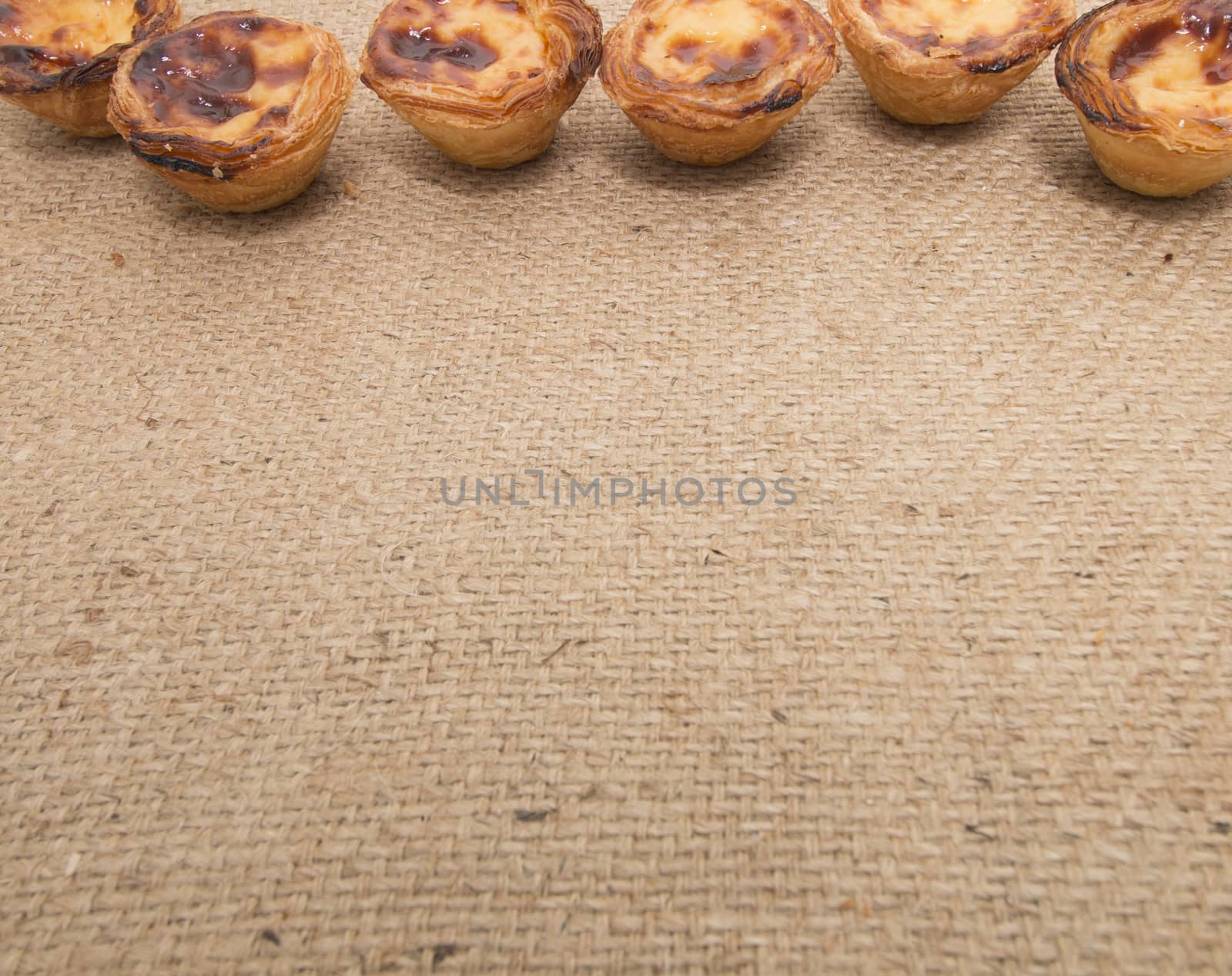 Famous Portuguese egg pastry tart called 'Pastel de Belem' on hessian fabric.