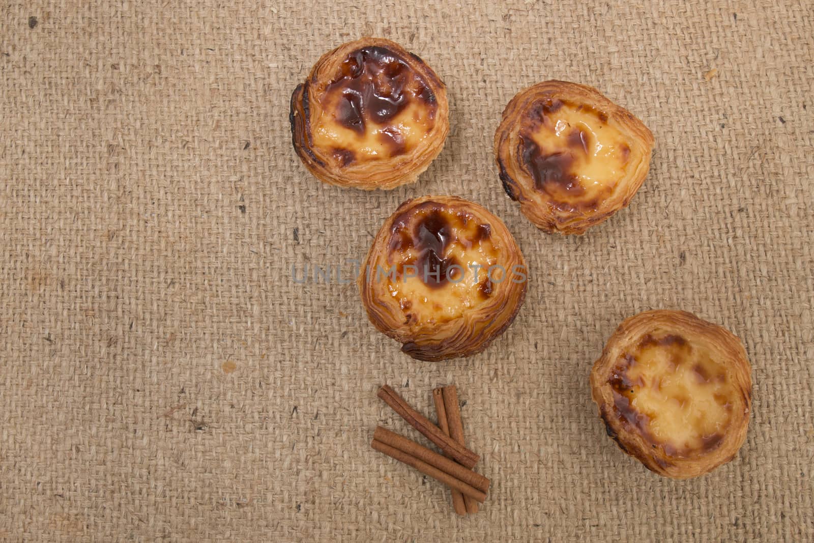 Famous Portuguese egg pastry tart called 'Pastel de Belem' on hessian fabric.