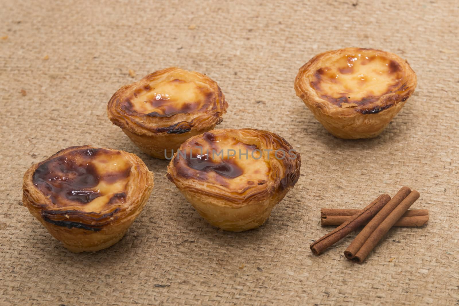 Famous Portuguese egg pastry tart called 'Pastel de Belem' on hessian fabric.