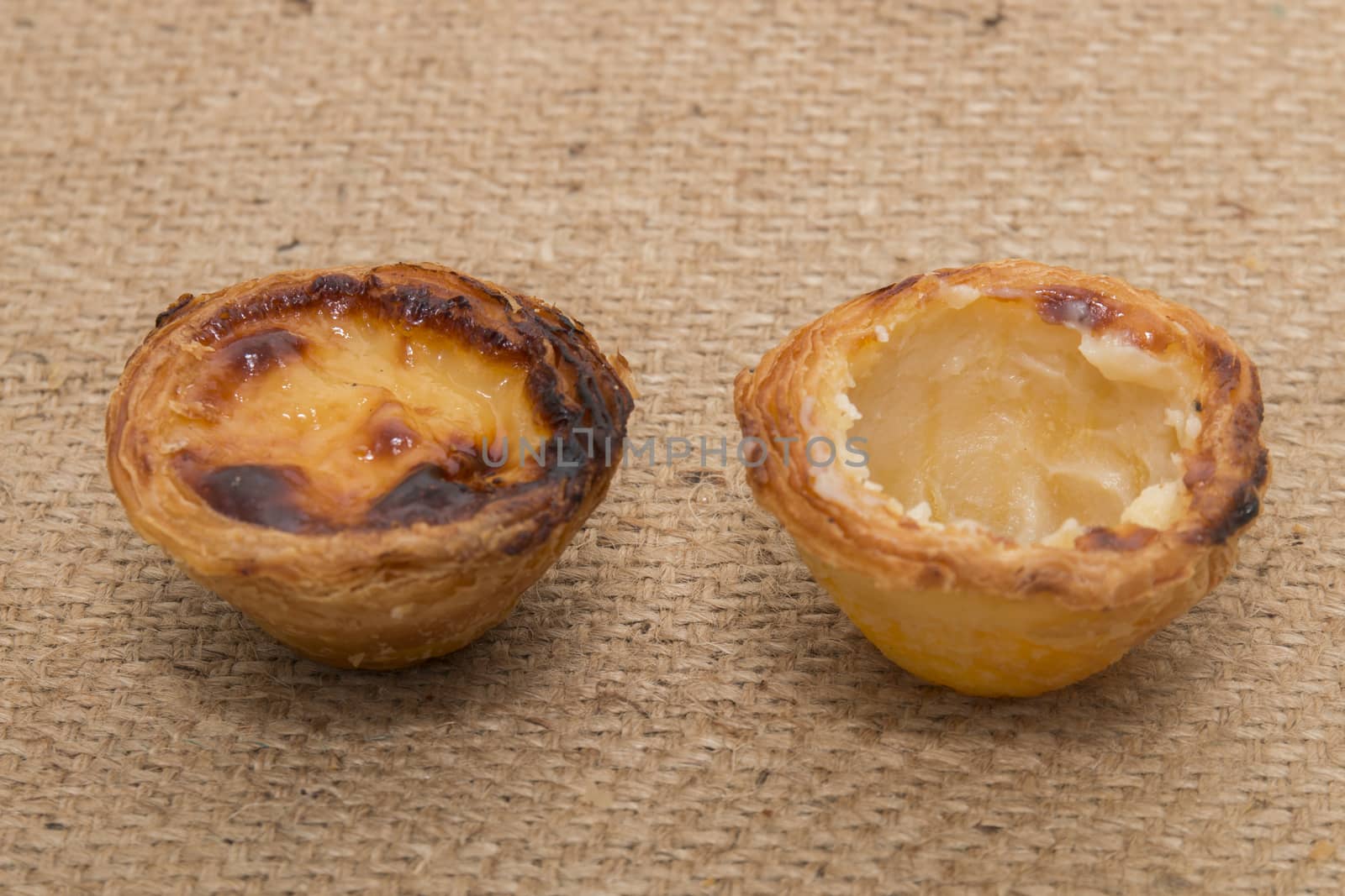 Famous Portuguese egg pastry tart called 'Pastel de Belem' on hessian fabric.