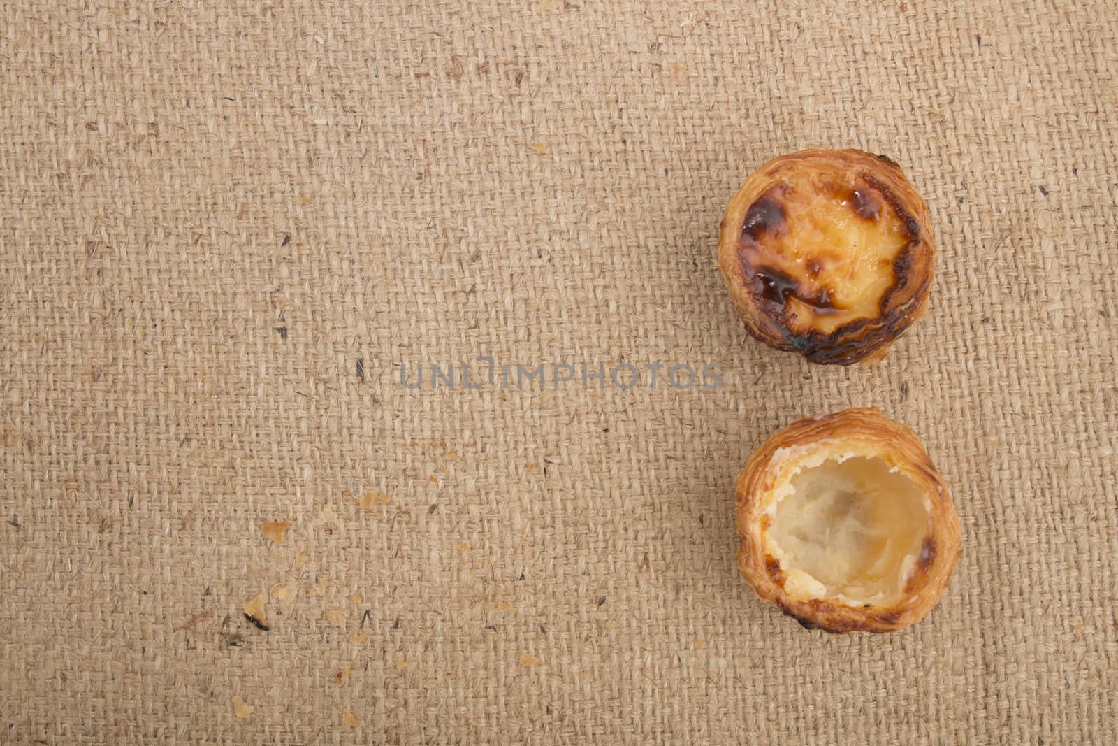 Famous Portuguese egg pastry tart called 'Pastel de Belem' on hessian fabric.
