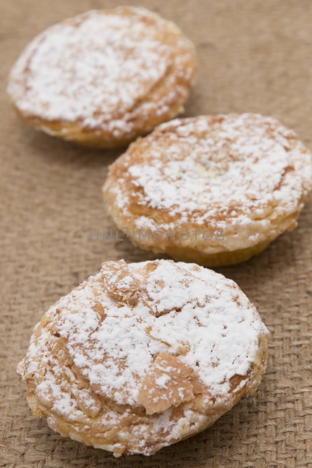 Famous Portuguese flaky Bean pastry sprinkled with white sugar powder on hessian fabric.