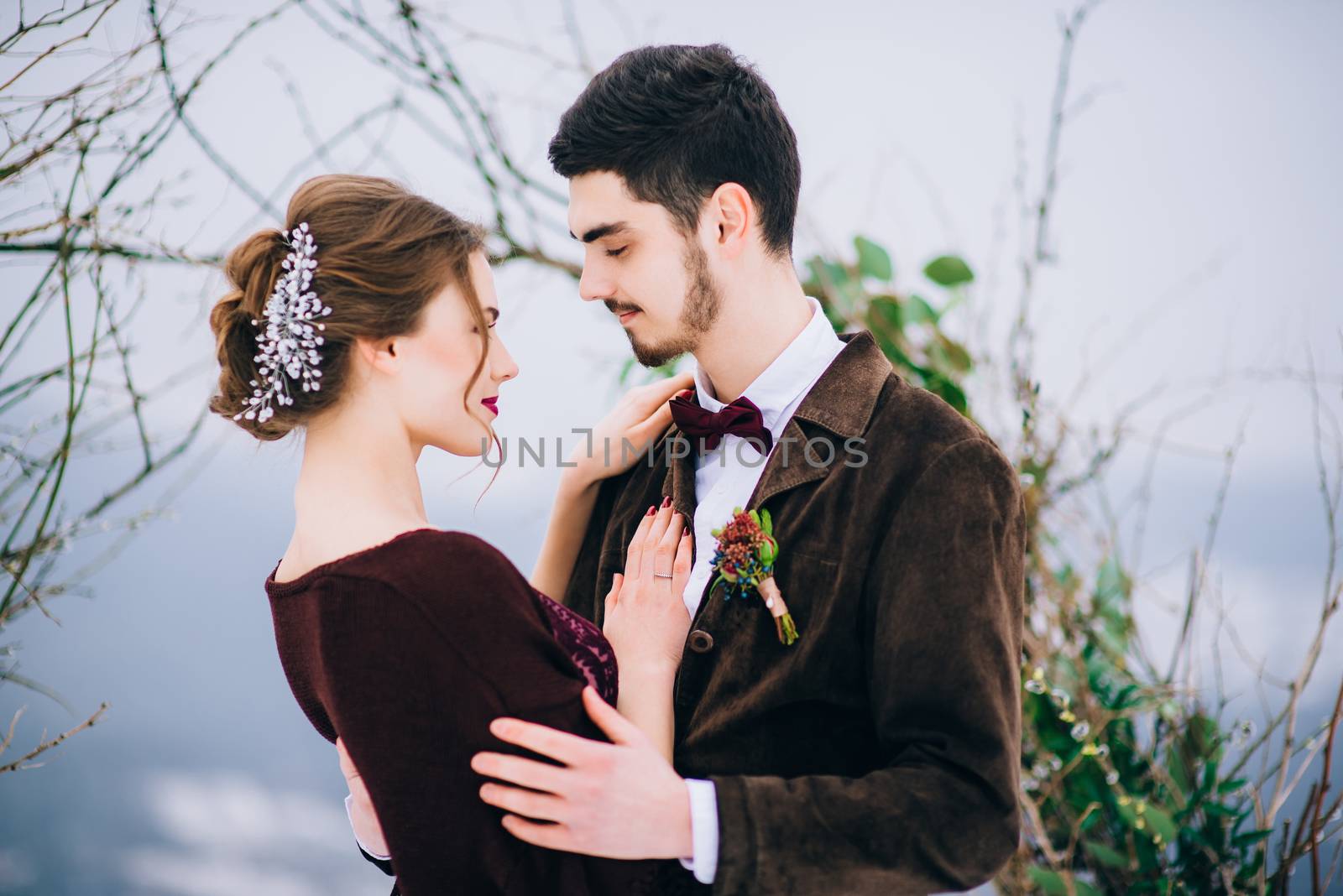 groom in a brown and bride in burgundy in the mountains Carpathians