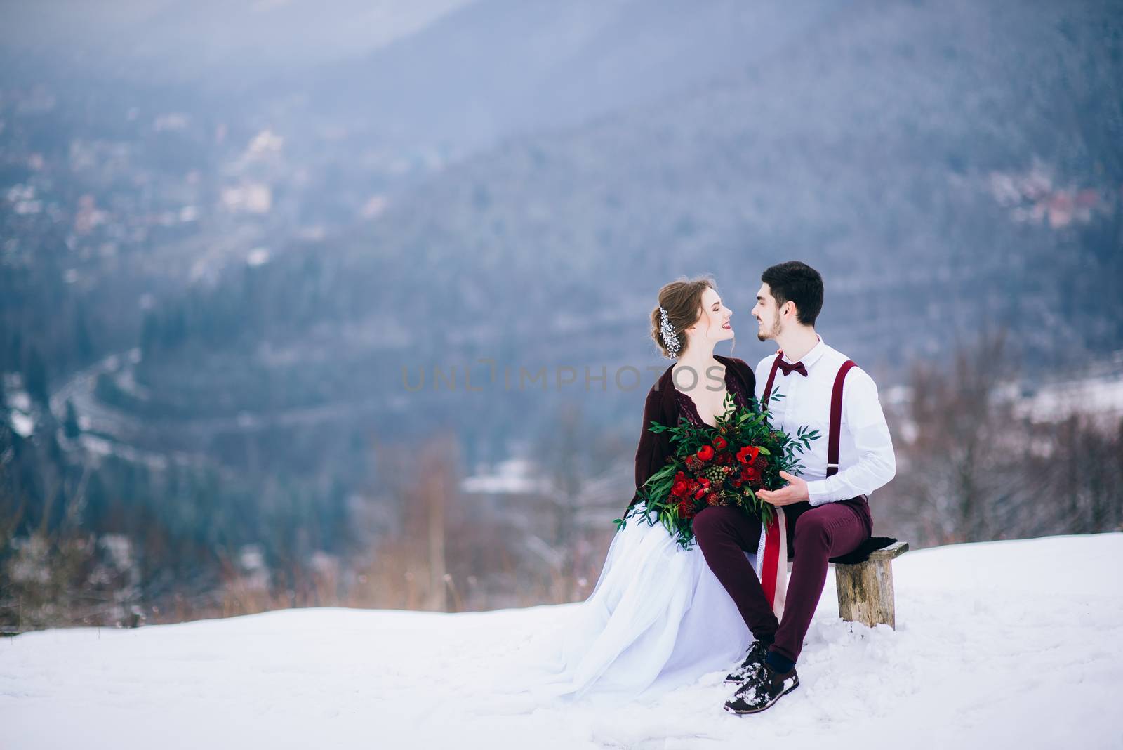 groom in a brown and bride in burgundy in the mountains Carpathians