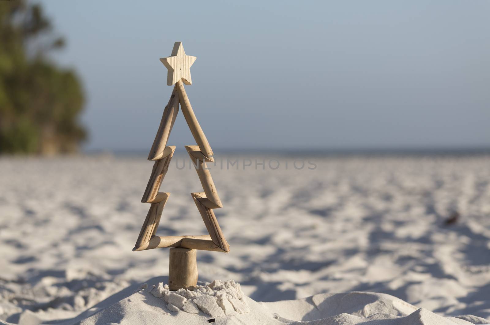 A driftwood Christmas tree in the sand on the beach in summer