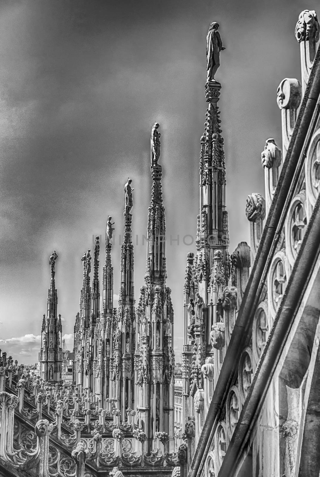 Detail with marble spiers and statues on the roof of the gothic Cathedral of Milan, Italy