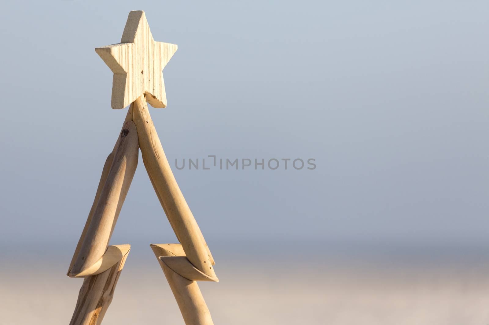 A wooden Christmas tree against a beach background with copy space.