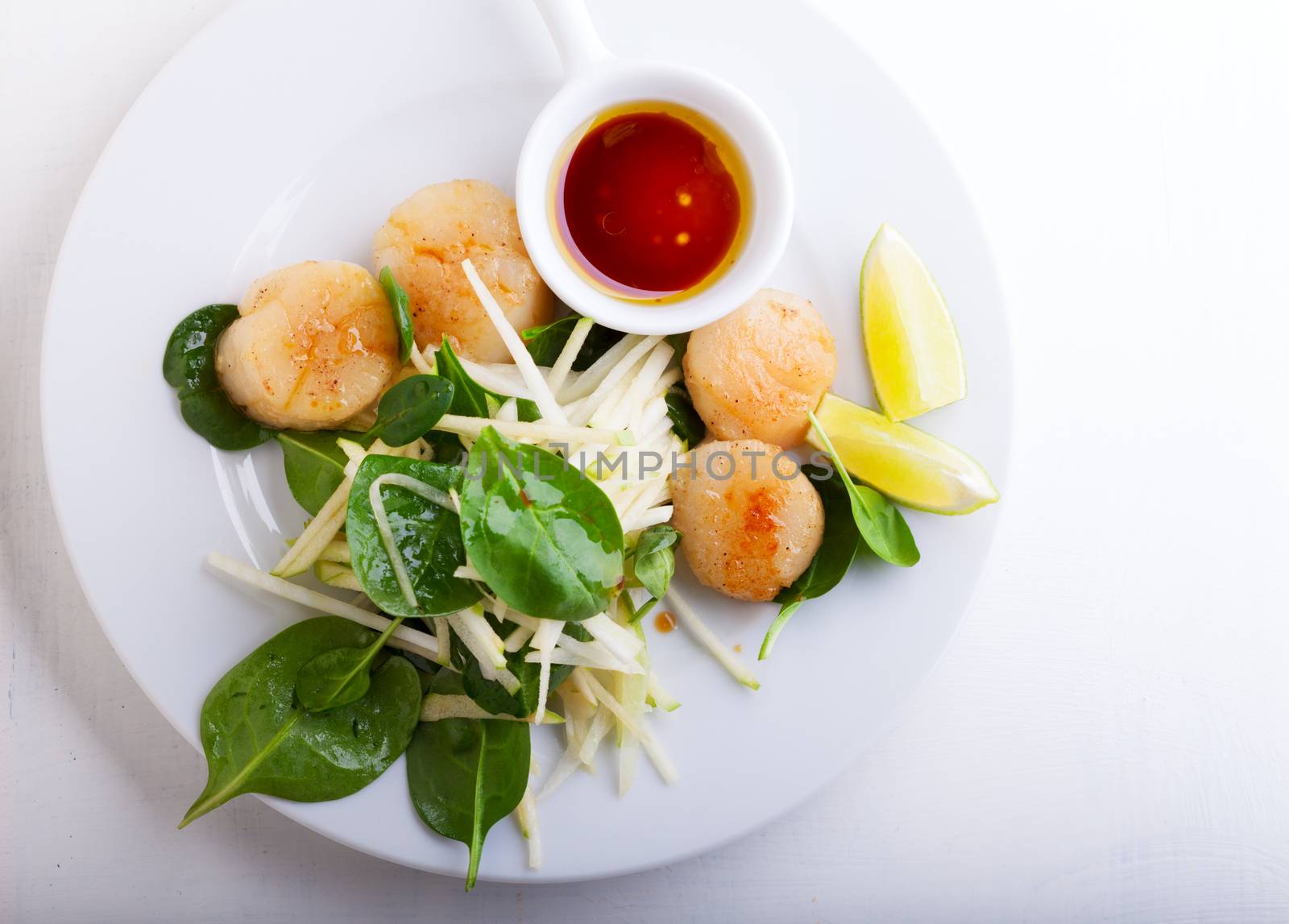 Scallop Salad with greenery served on a white plate