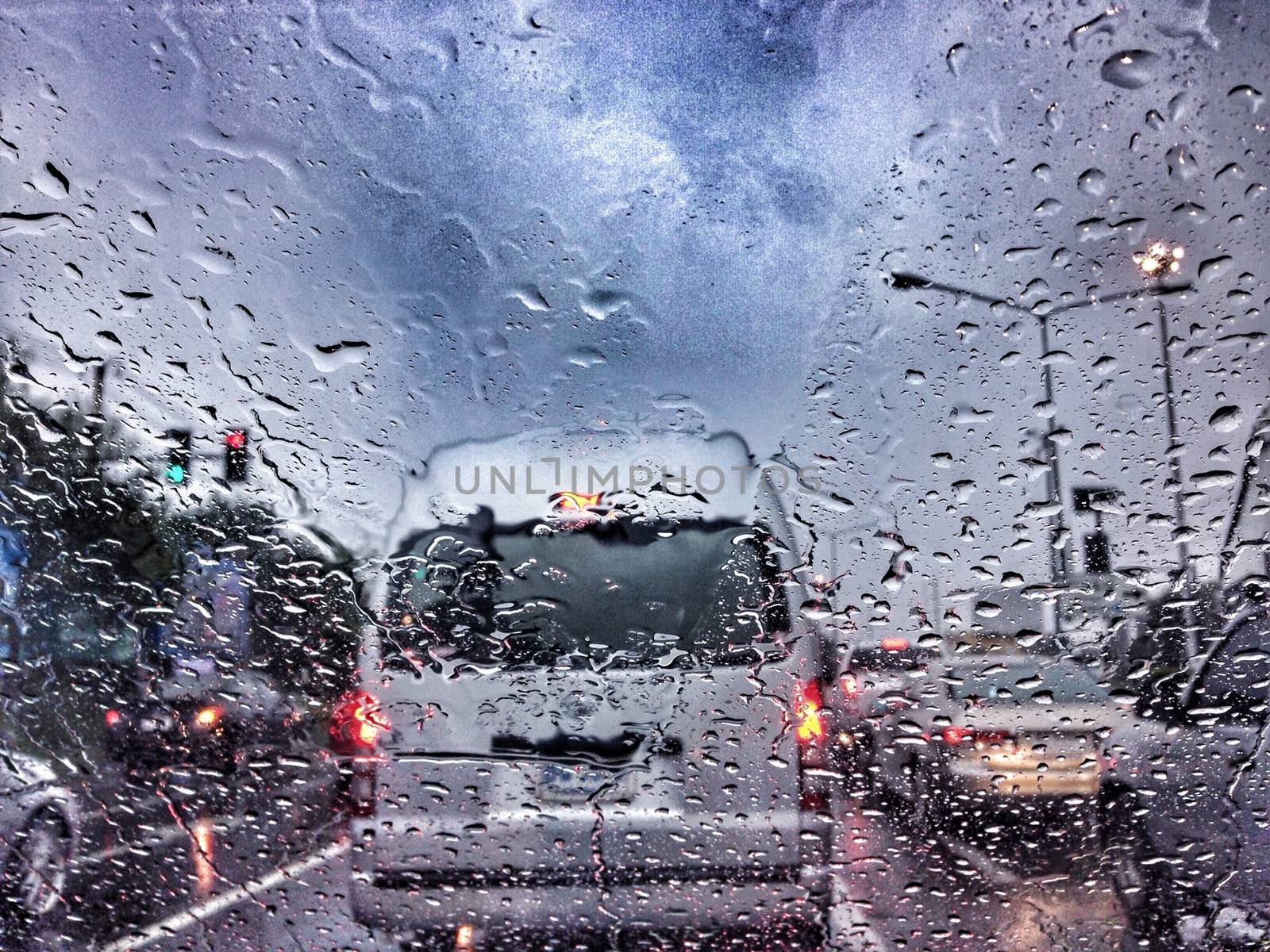 Traffic stands still on a rainy day with road view through car window with rain drops