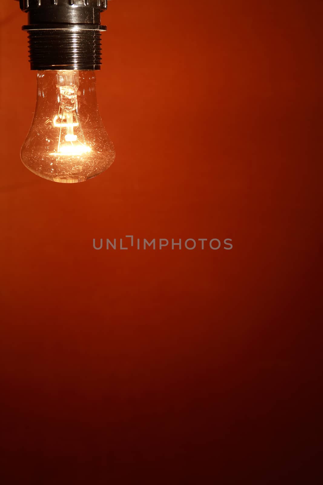 Closeup of glowing light bulb on nice red wall background