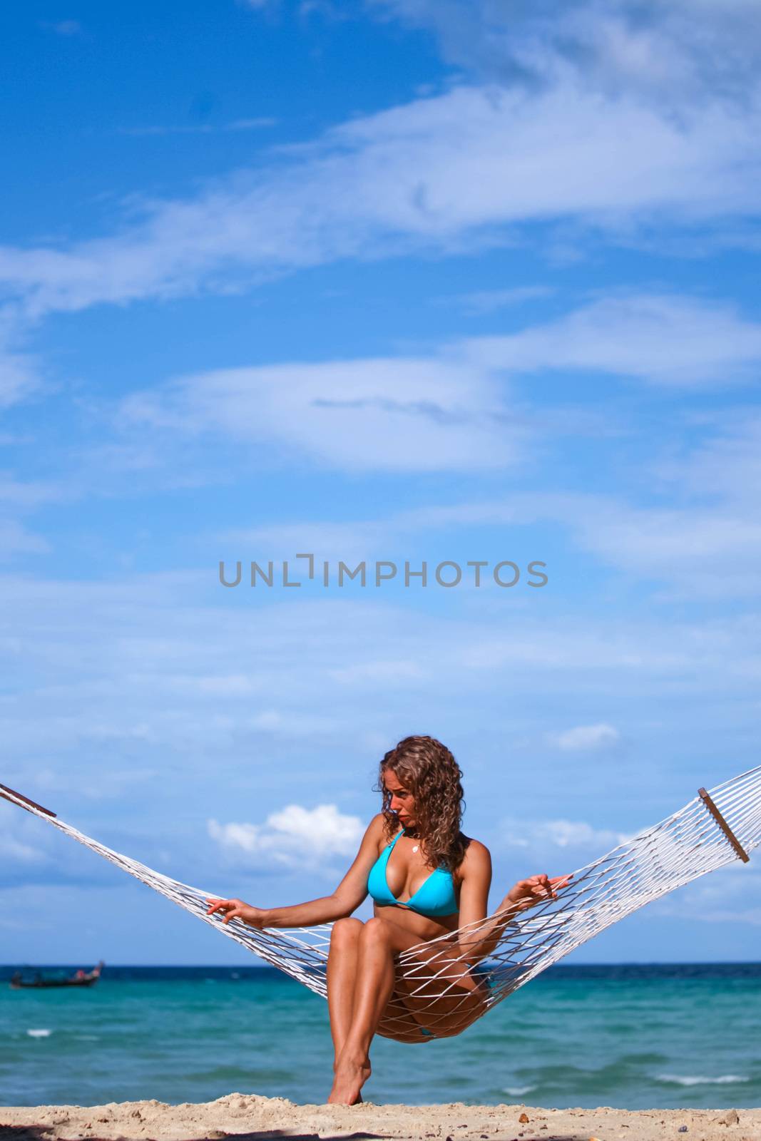 Young woman swinging in hummock on blue sea background