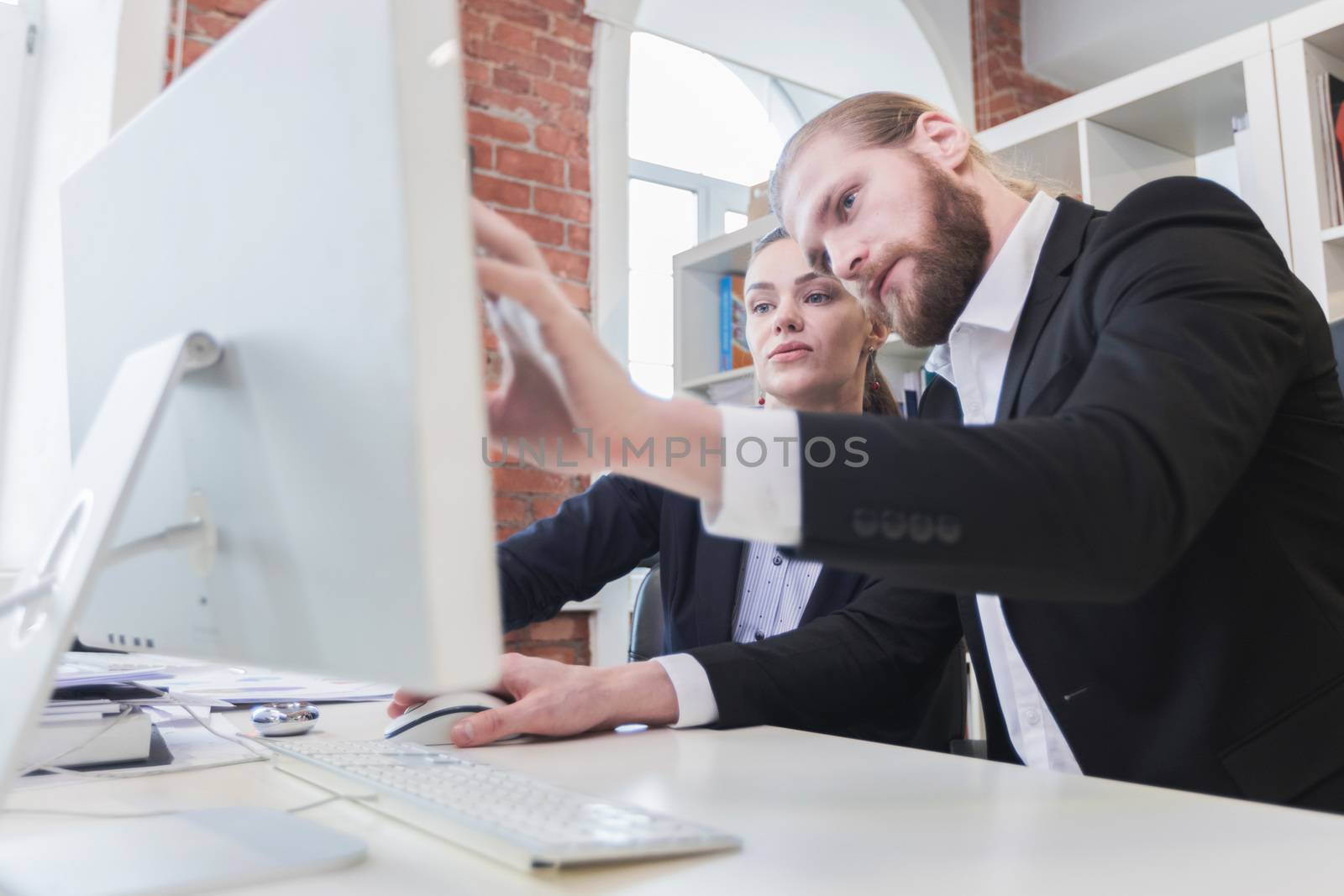 Two business people looking at monitor sitting in office