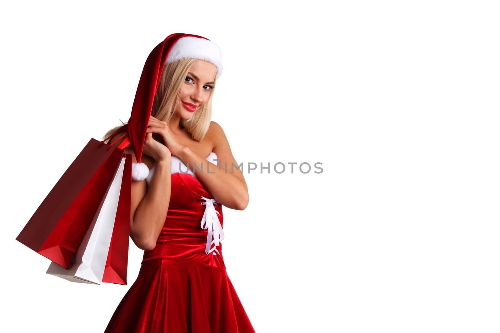 Cute young girl in santa claus costume holding paper shopping bags isolated on white background