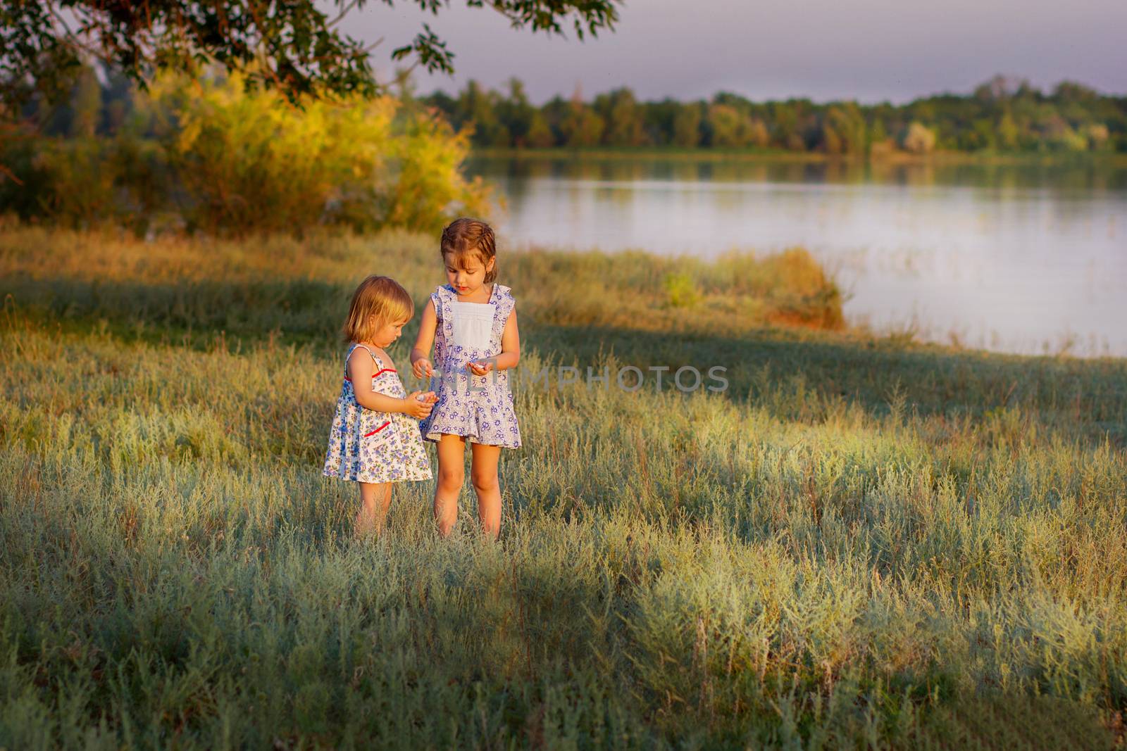girls play the field at a pond at sunset