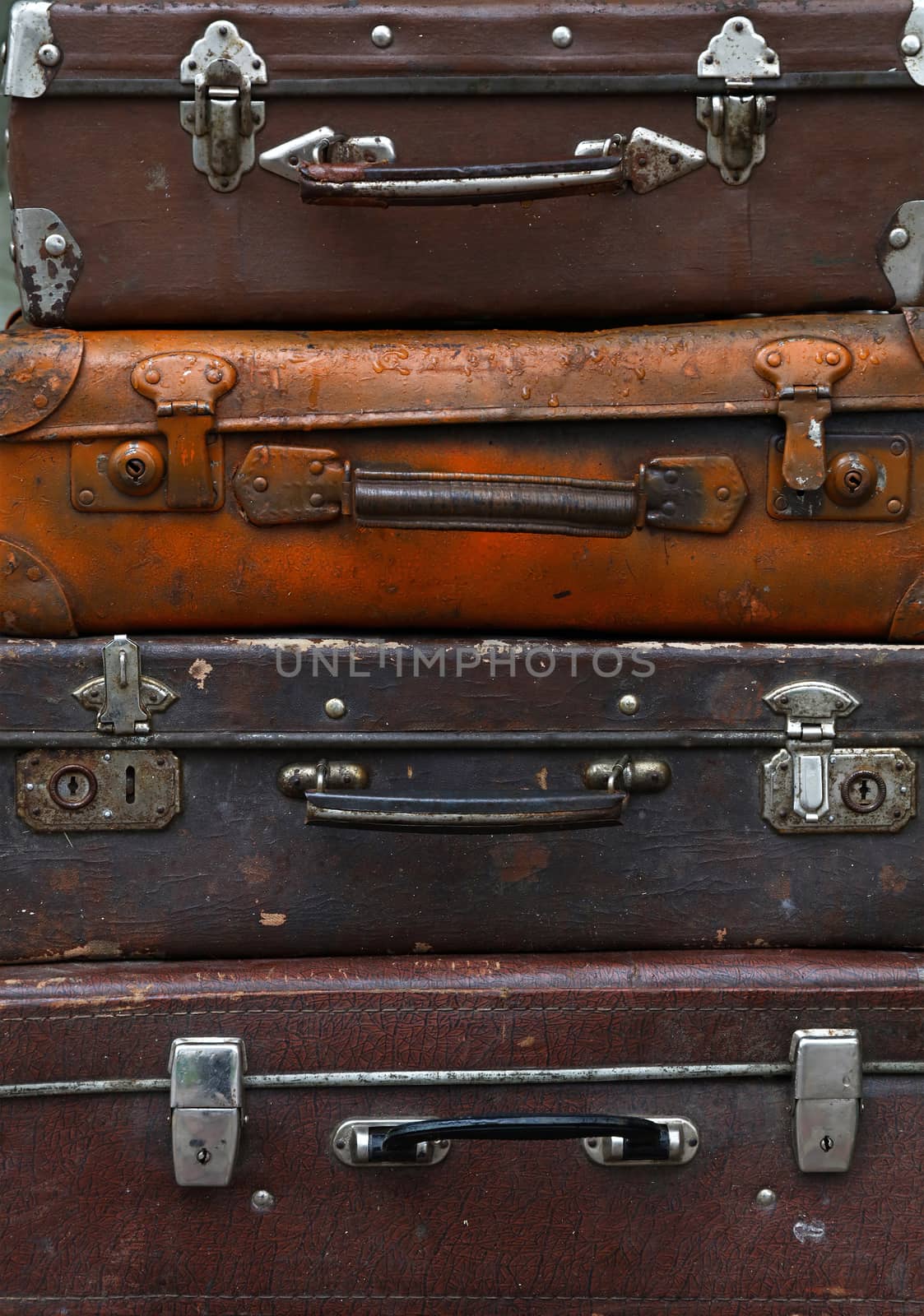 Stack of four old vintage antique grunge travel luggage brown leather suitcase trunks, close up, low angle front view