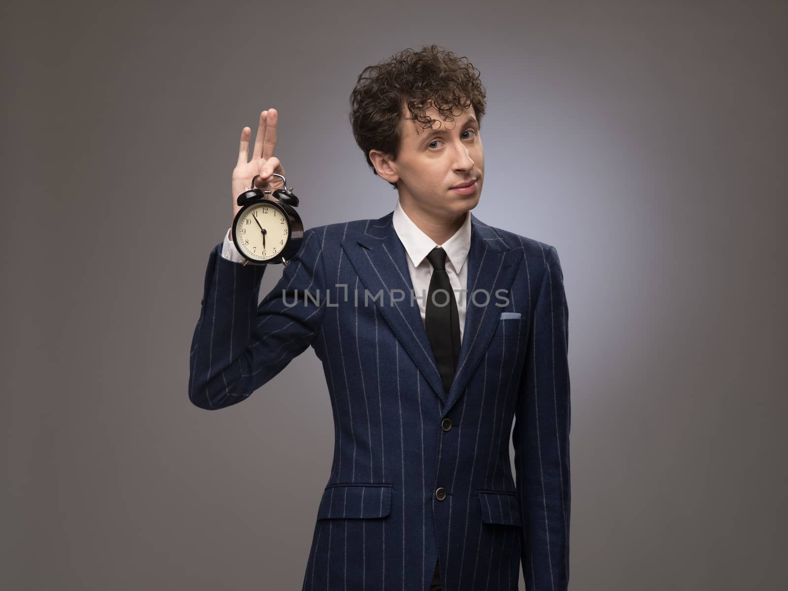 Funny businessman holding alarm clock showing time of deadline