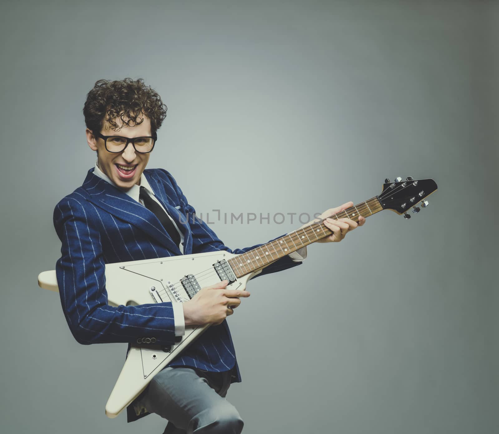 Funny man in striped suit with funny facial expression playing electric guitar