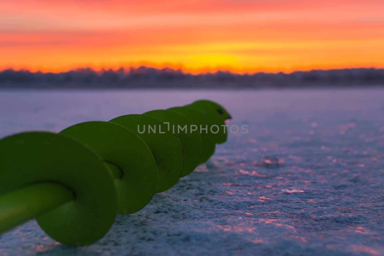 Fishing ice auger at dawn fishing drill ice beautiful sky