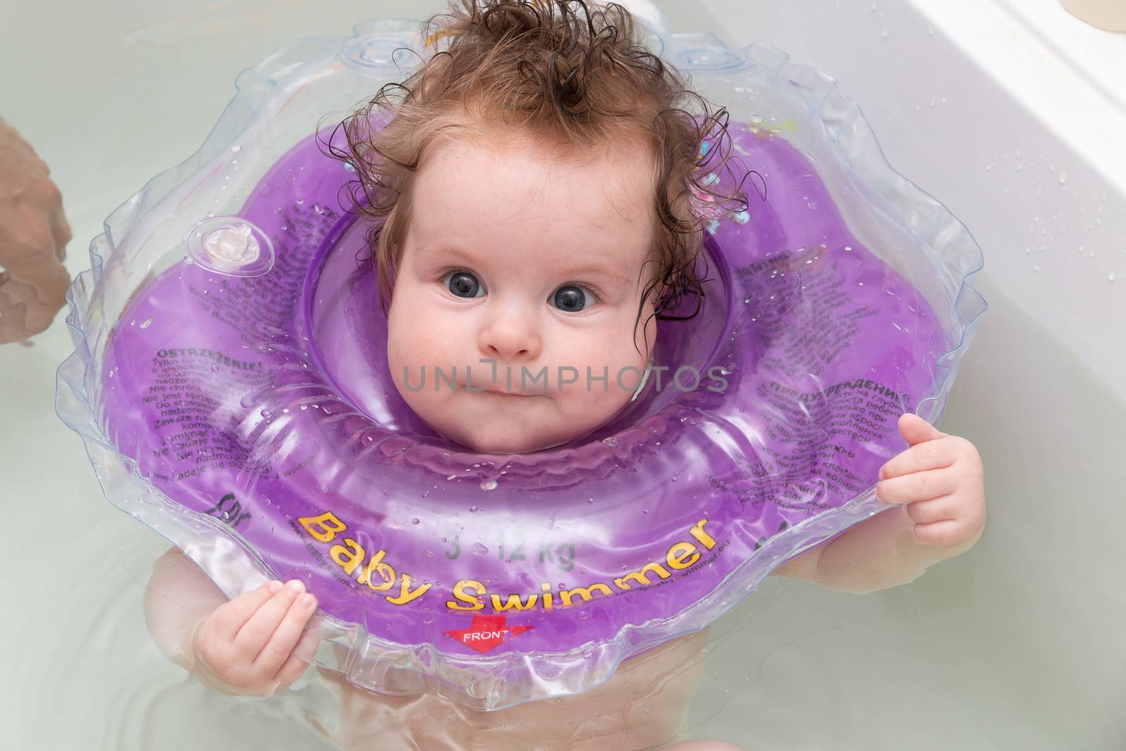 Baby swimming in bath with neck swim ring. by MSharova