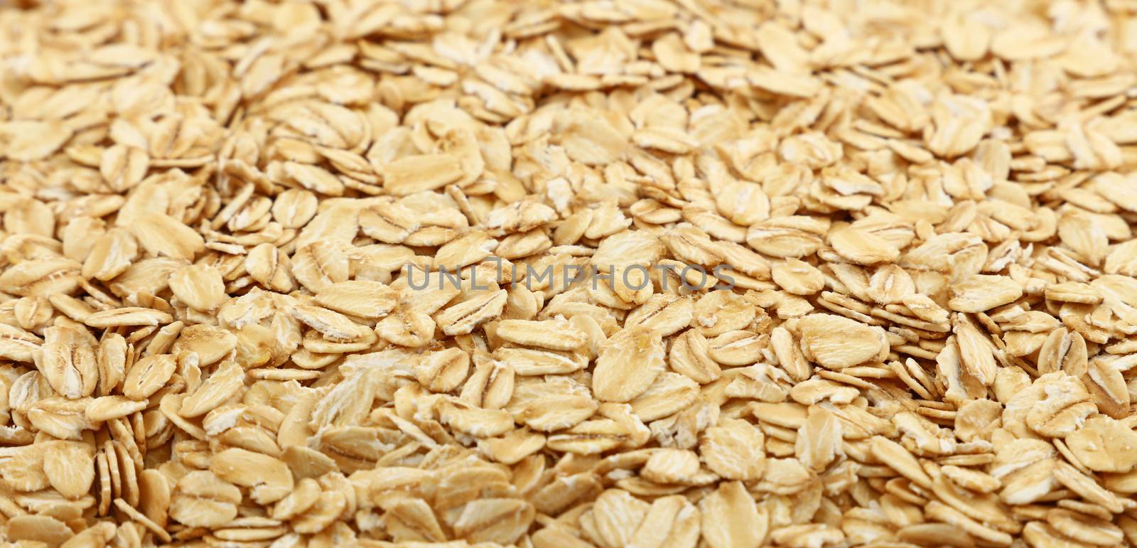 Flakes of porridge oat grits for oatmeal close up pattern background, low angle view, selective focus