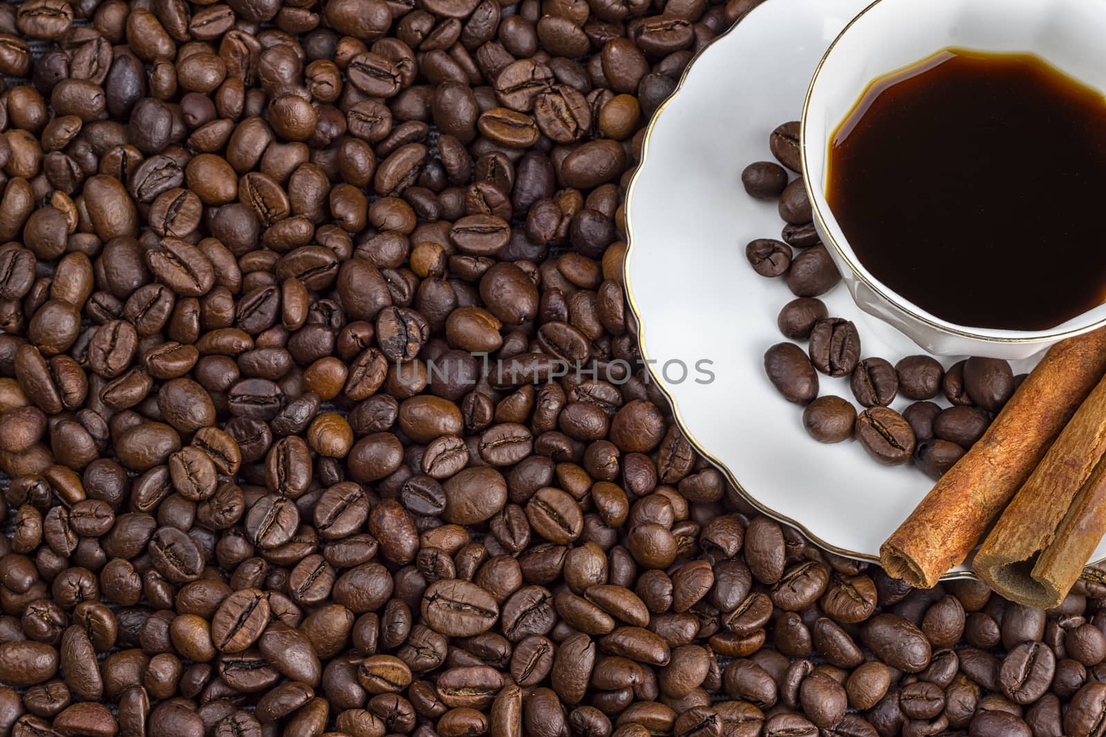 A cup of coffee with beans as background. and cinnamon 