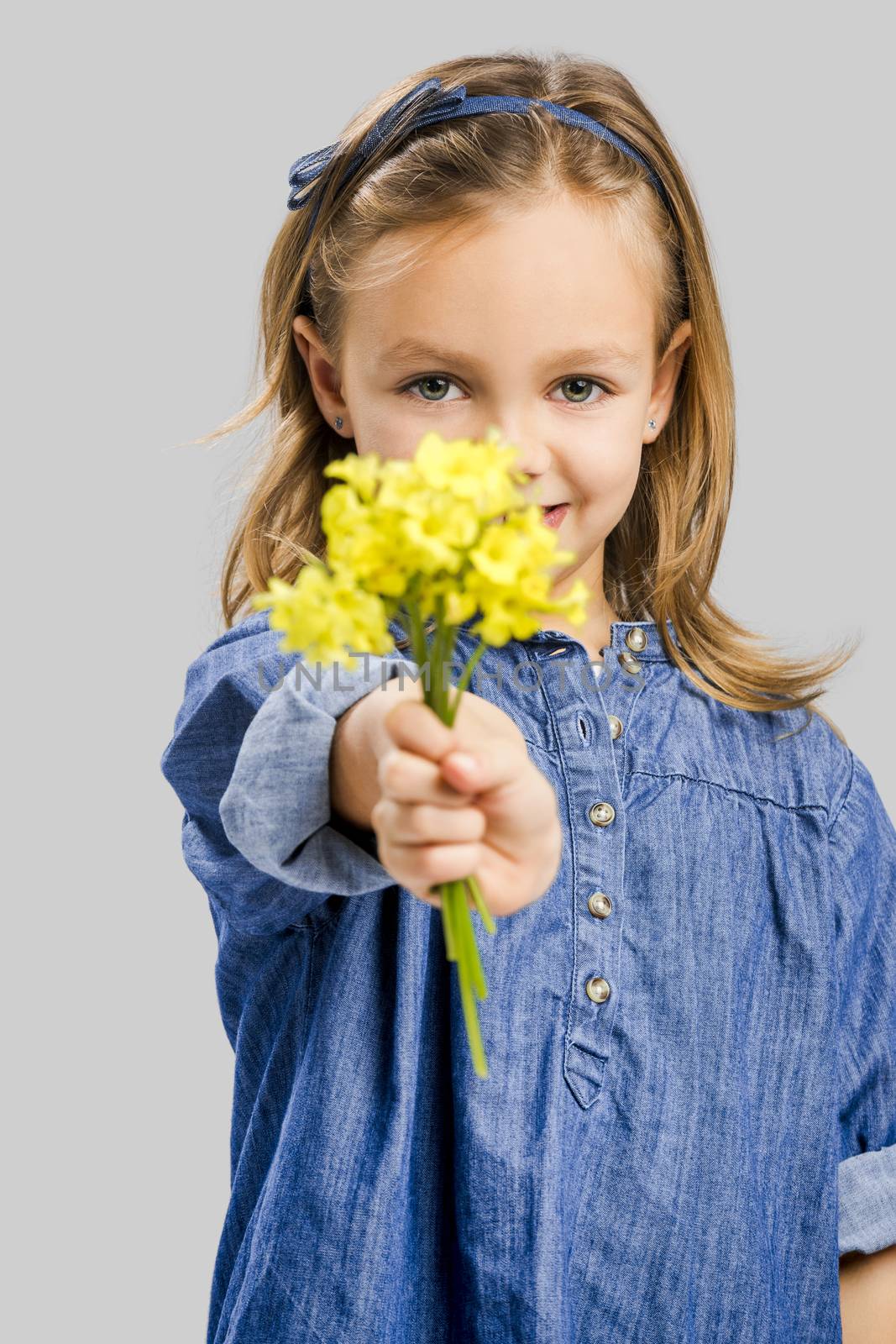 Studio portrait of a beautiful cute girl holding wild flowers
