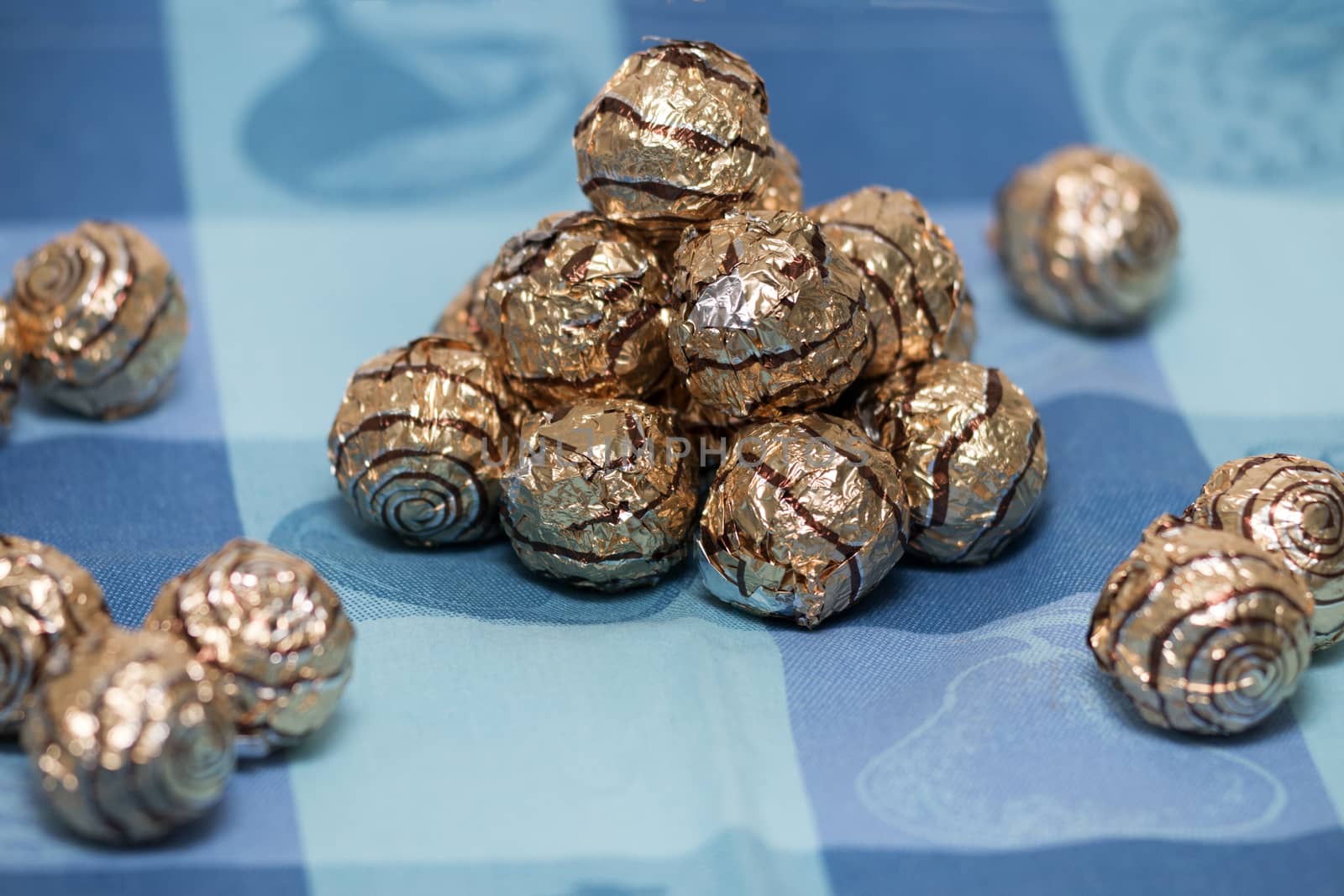 Pile of sweet round chocolate candies for christmas celebrations on a table cloth.
