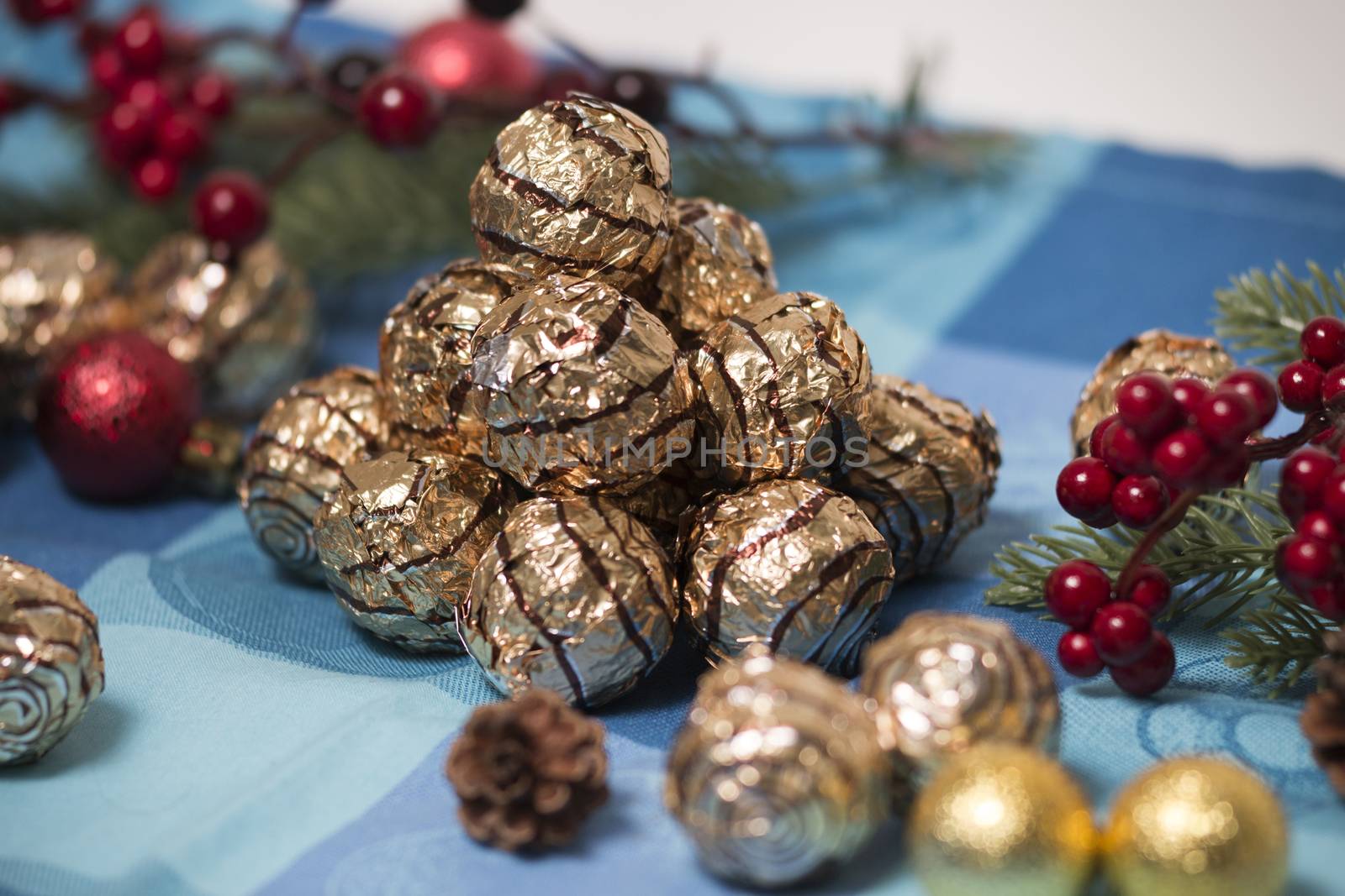 Pile of sweet round chocolate candies for christmas celebrations on a table cloth.