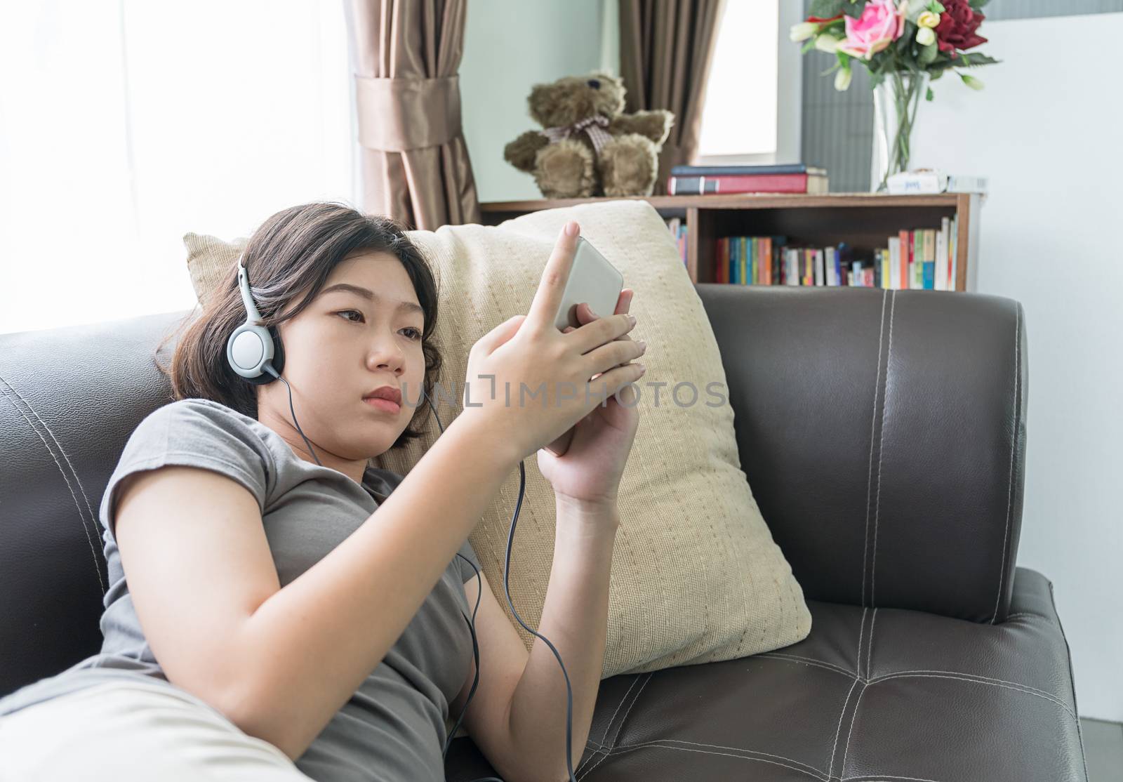 Close up young asian woman short hair listening music from mobile phone on the couch at home