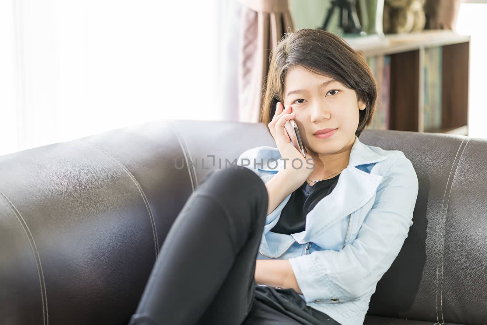 Close up young asian woman short hair use mobile phone on the couch in living room at home