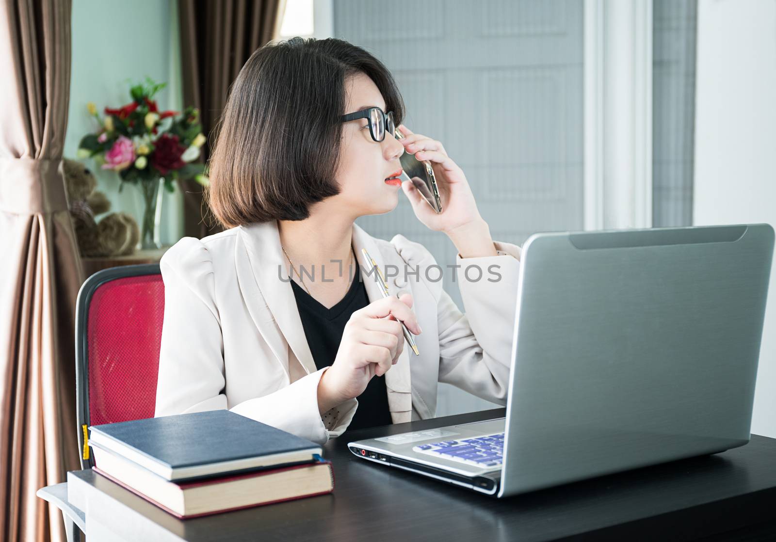 Woman short hair in smart casual wear working on laptop while sitting near window in home office