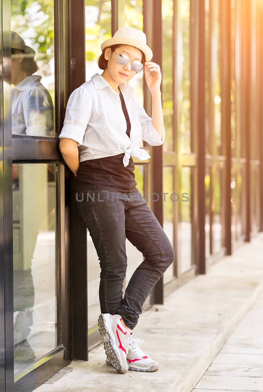 Women wearing hat standing in front of a glass building by stoonn