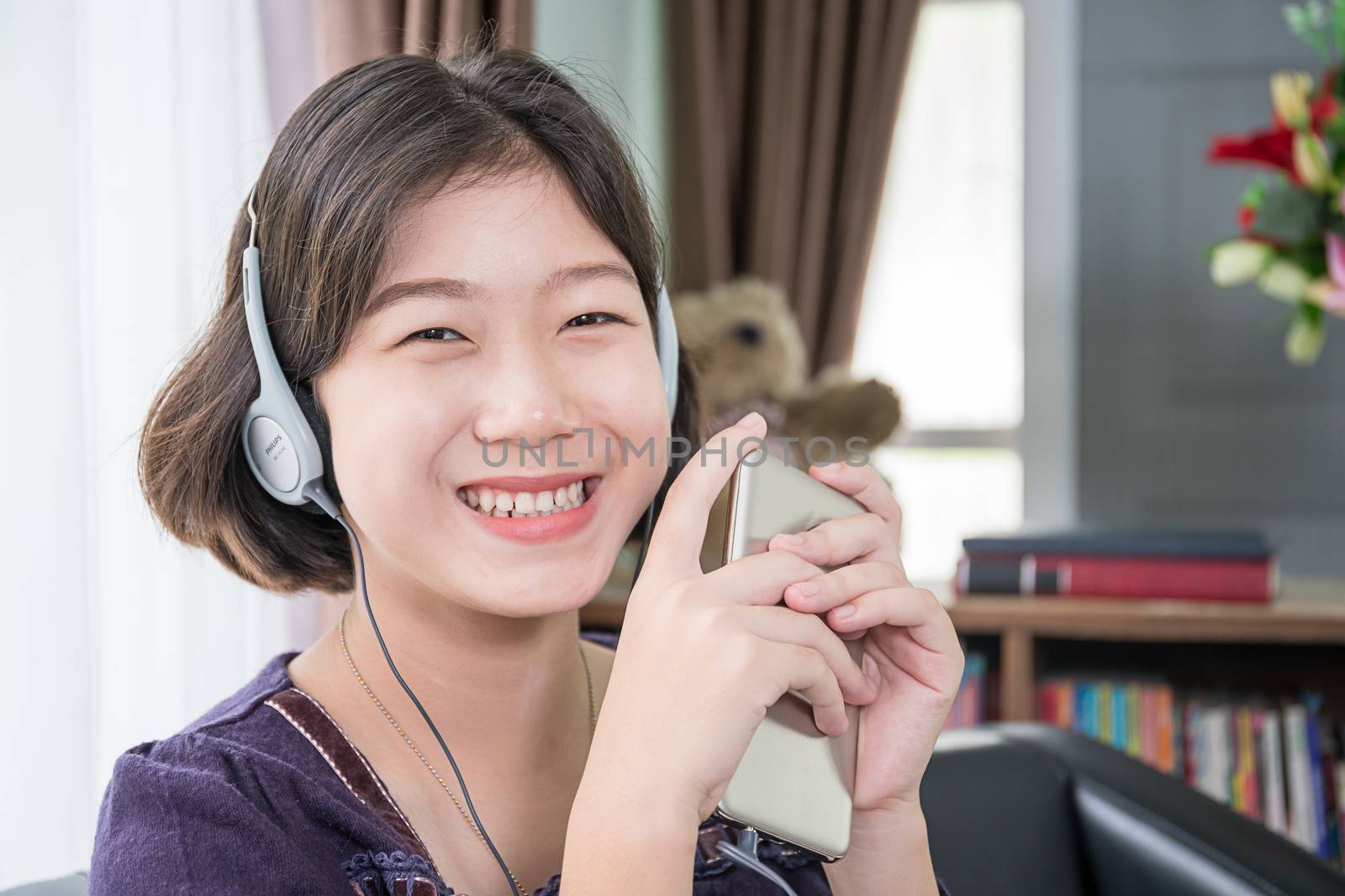 Young asian woman short hair listening music in living room by stoonn