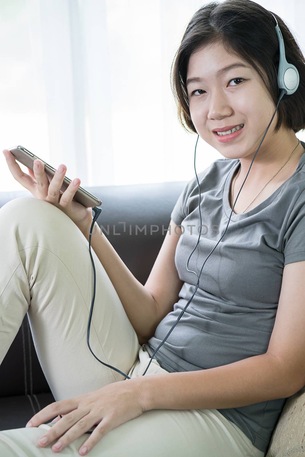 Close up young asian woman short hair listening music from mobile phone on the couch