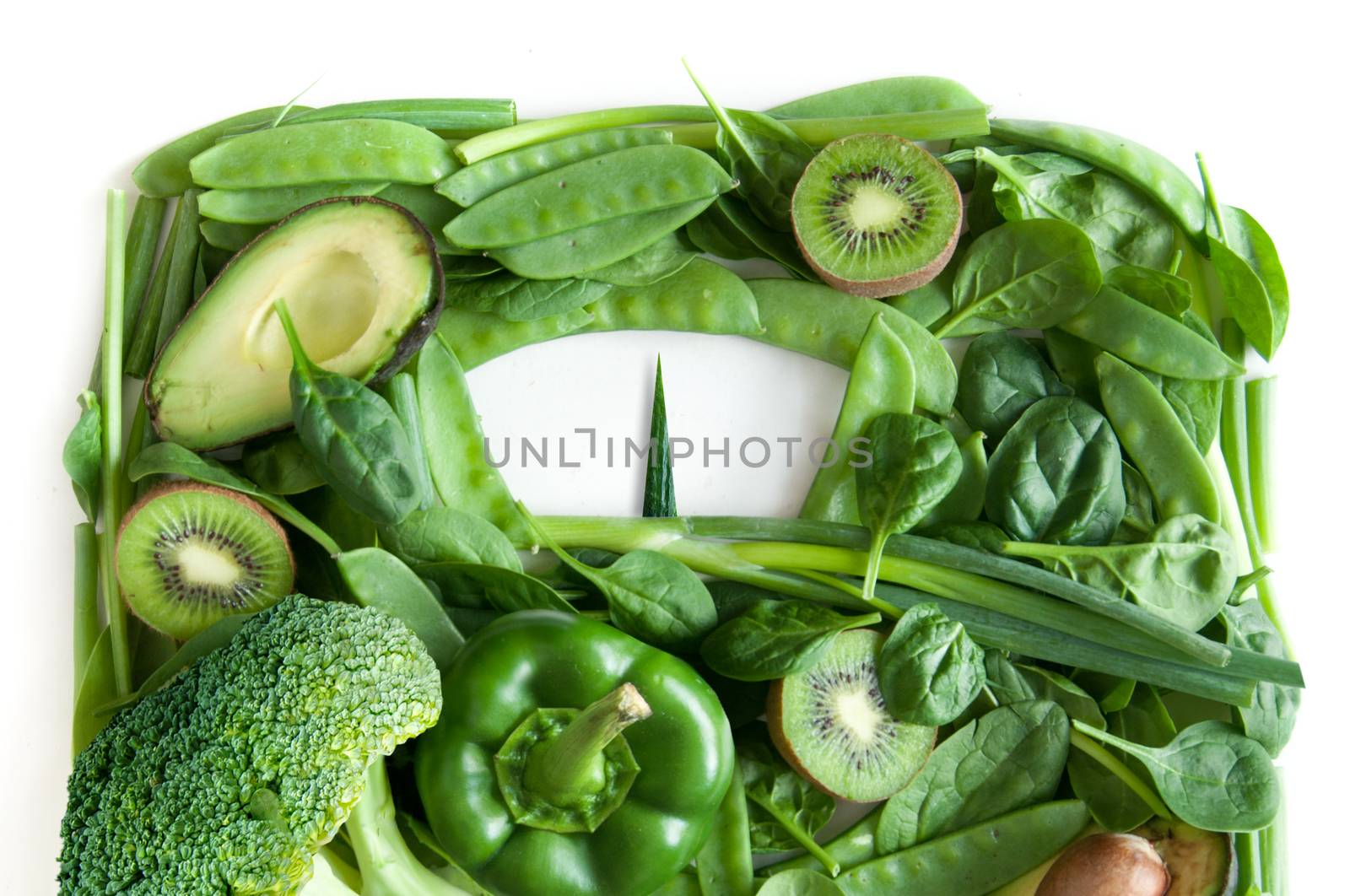 Green fruits and vegetables in the shape of bathroom weighing scales over a white background