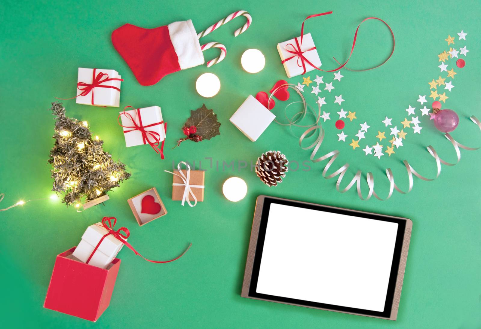 Christmas gifts, baubles, and decorations coming out of a gift box with a blank tablet 