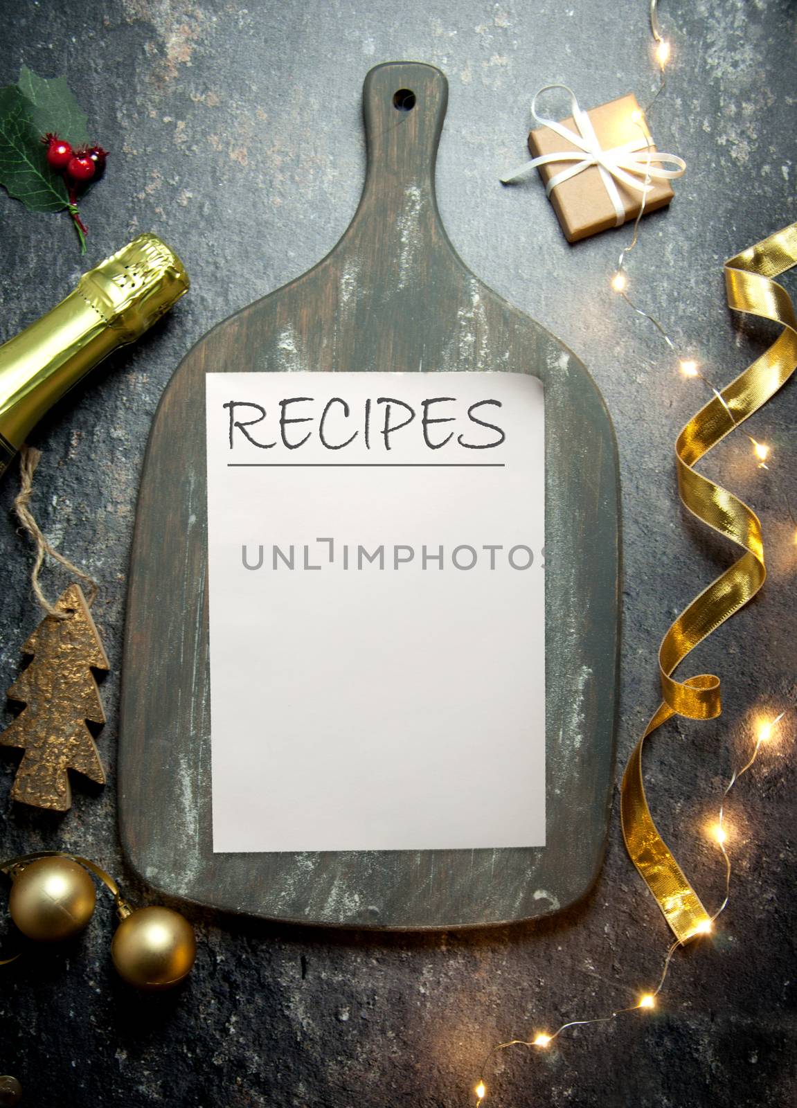 Recipes handwitten on a piece of paper on top of a rustic chopping board with decorations and champagne bottle