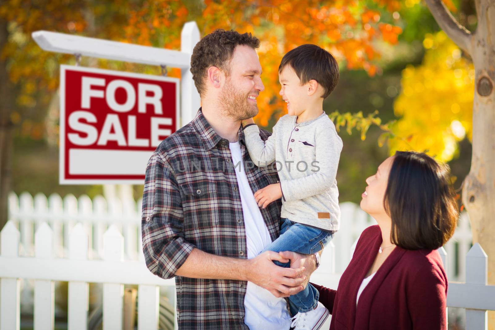 Mixed Race Chinese and Caucasian Parents and Child In Front of Fence and For Sale Real Estate Sign.
