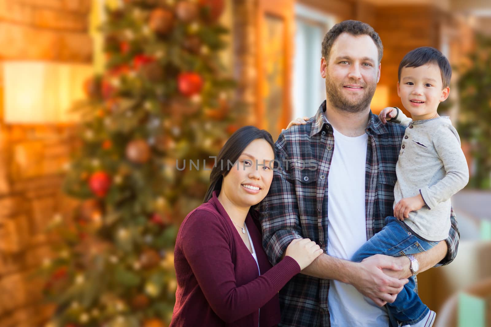 Mixed Race Chinese and Caucasian Parents and Child Indoors In Front of Christmas Tree.