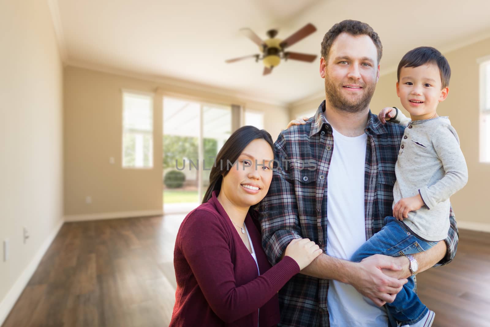 Mixed Race Chinese and Caucasian Parents and Child Inside Empty Room of New House.