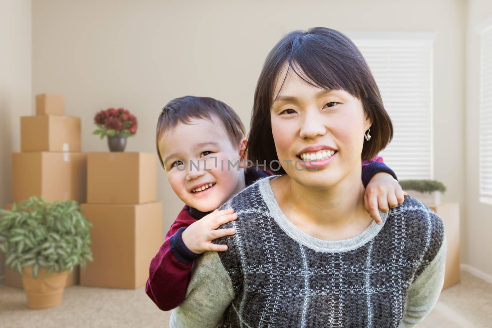 Chinese Mother and Mixed Race Child Inside Empty Room with Moving Boxes and Plants. by Feverpitched