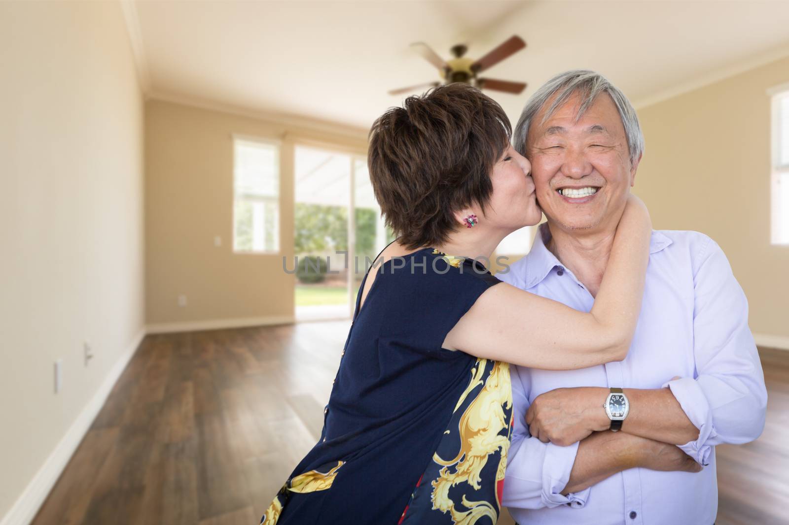 Happy Senior Chinese Couple Kissing Inside Empty Room Of New Hou by Feverpitched