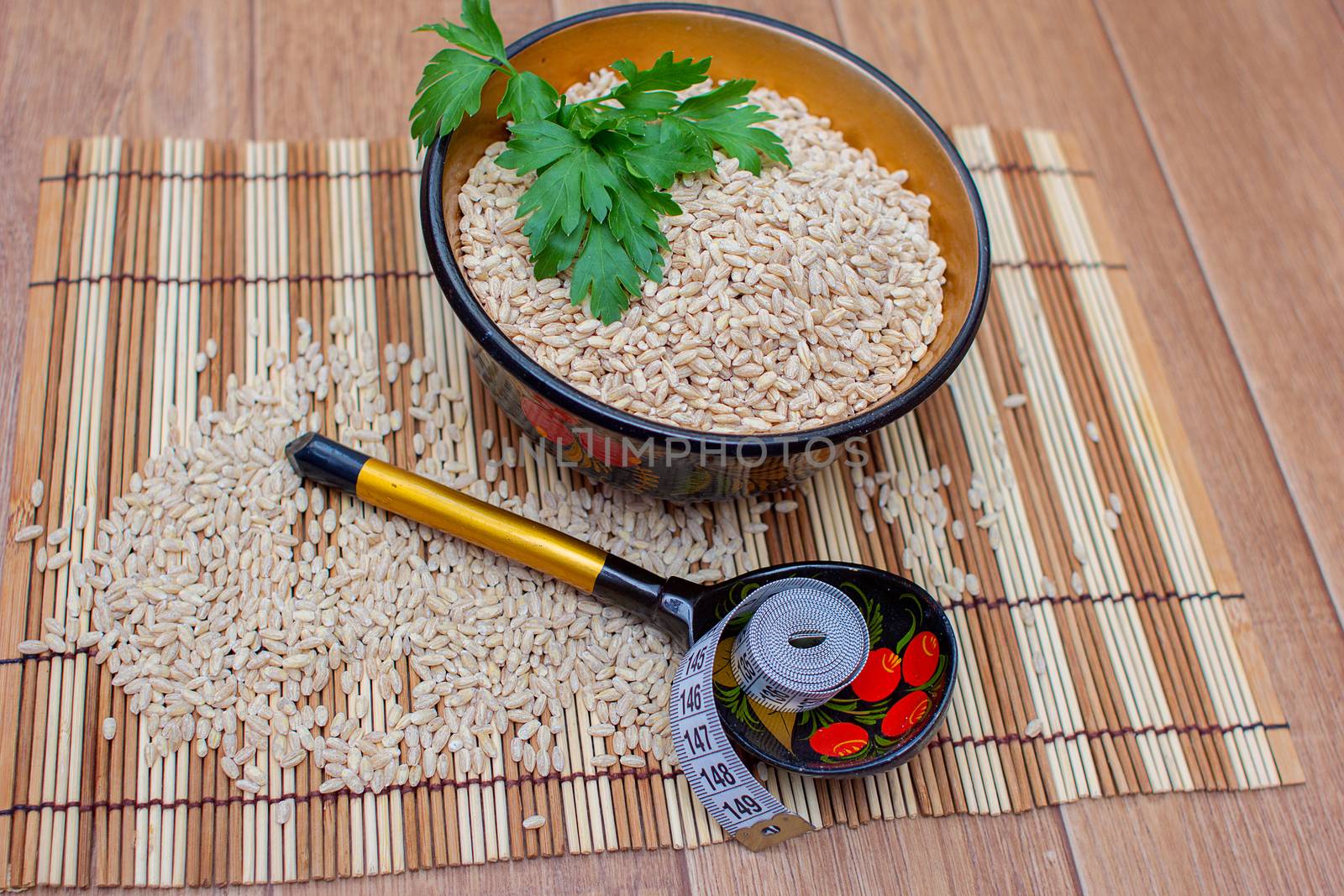 Pearl barley in a cup, nearby a wooden spoon and a centimetric tape