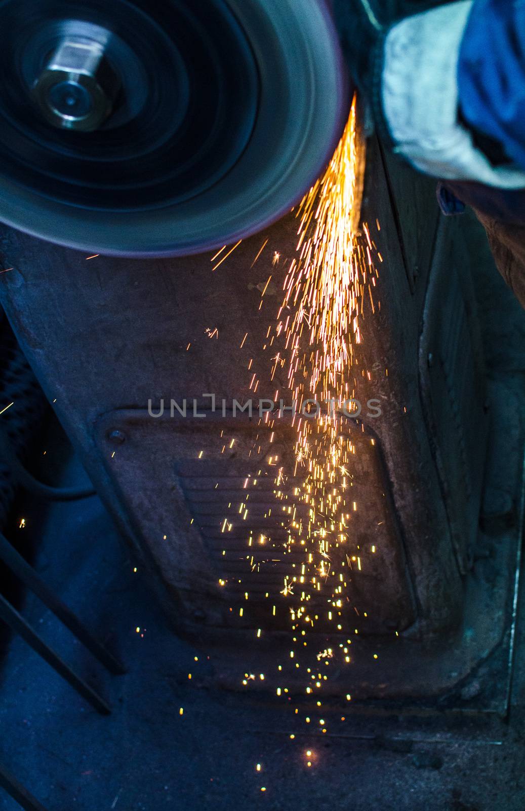 Industrial grinder showers sparks while working with metal.