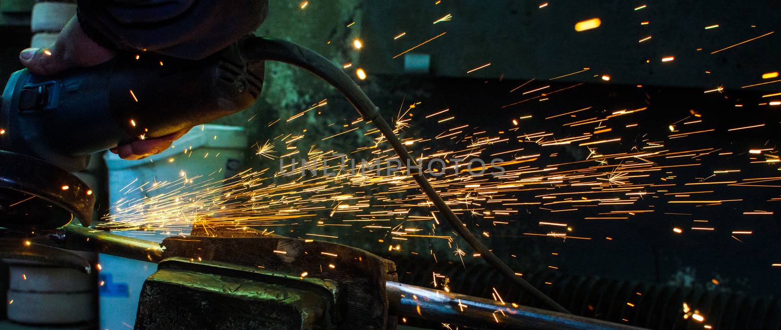 Industrial grinder showers sparks while working with metal.