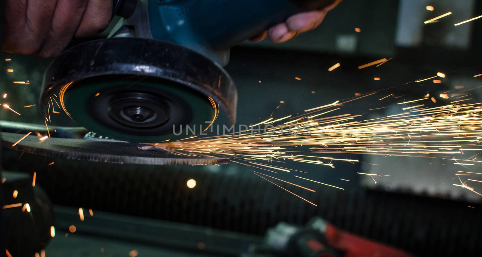 Industrial grinder showers sparks while working with metal.